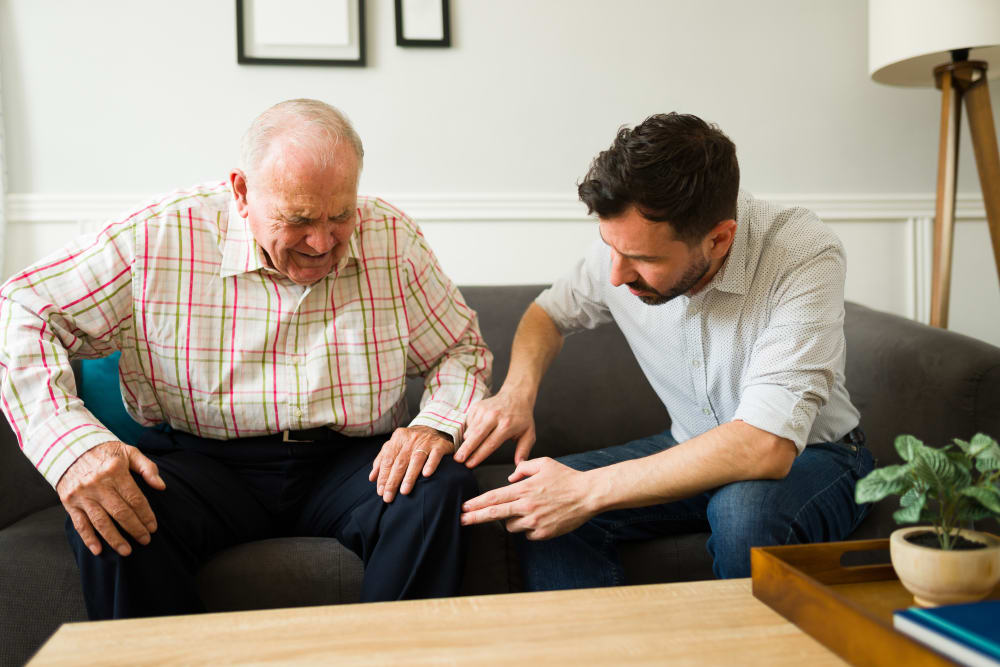 Son checking the knee pain of his elderly father